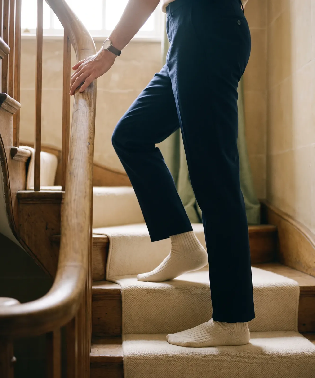 Climbing a carpeted staircase, one hand on the banister