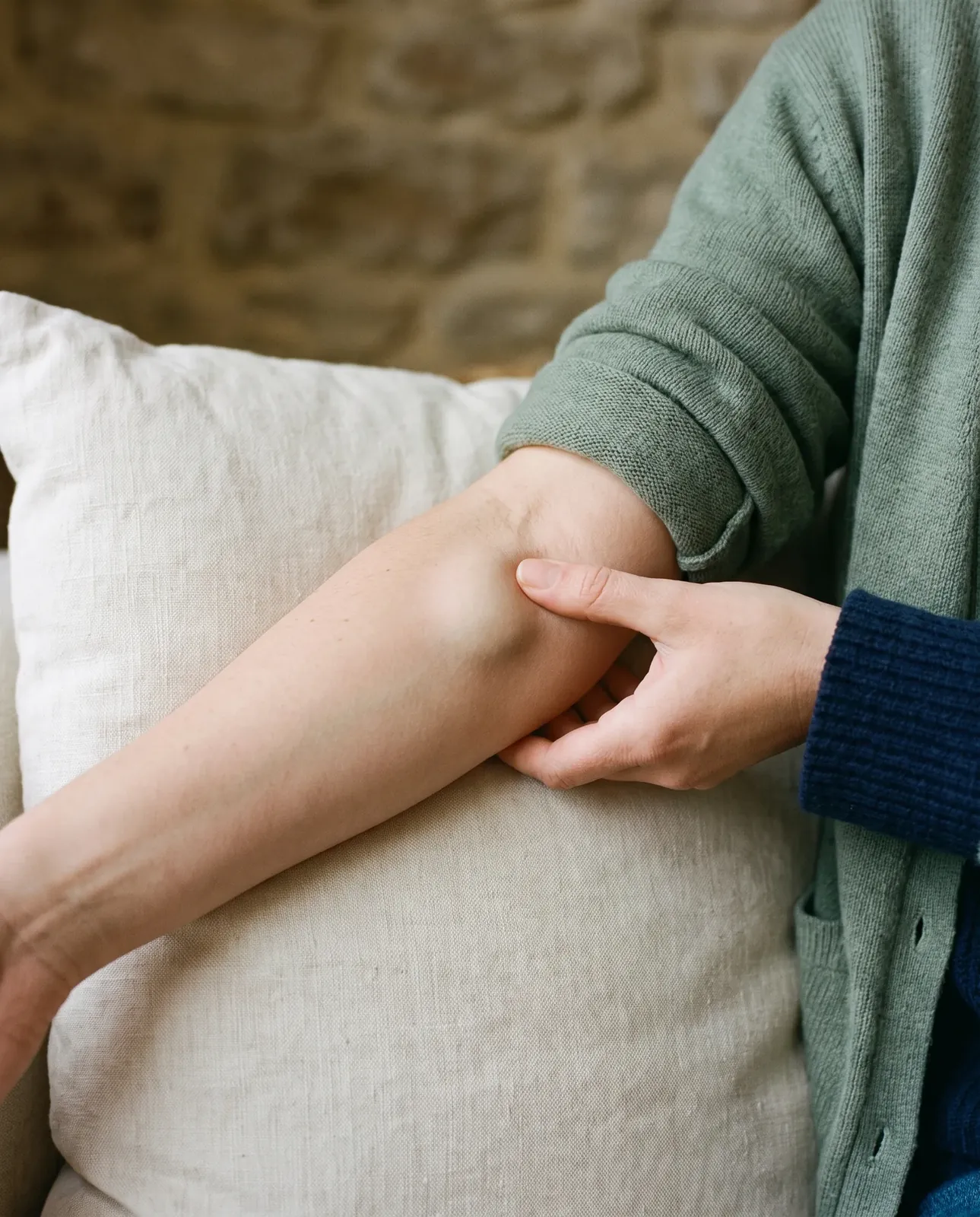 Fingers gently pressing a soft, rounded lump under the skin of a forearm