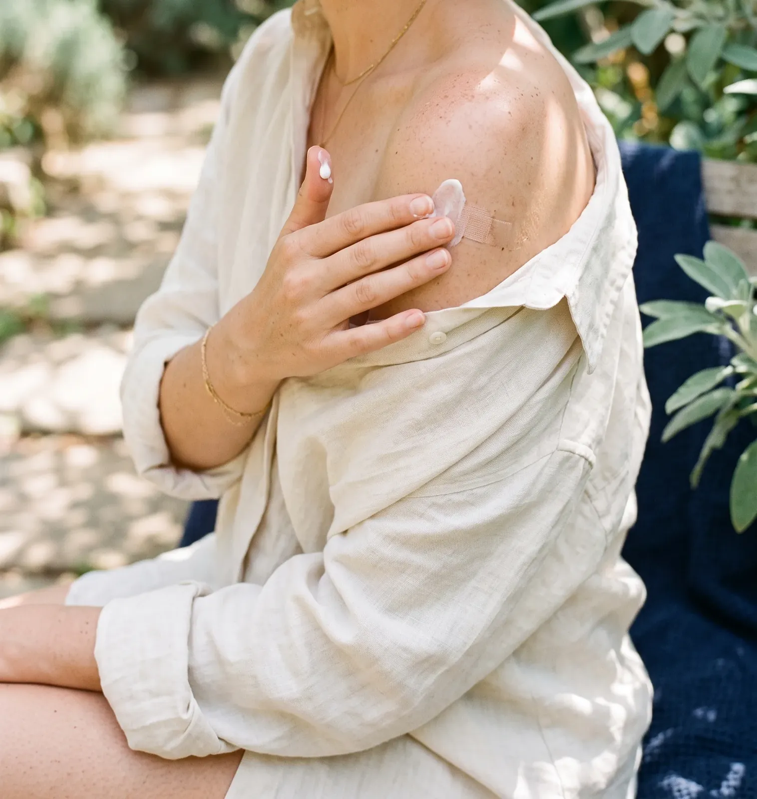 Hands smoothing a little sun cream onto a bare shoulder in soft summer light
