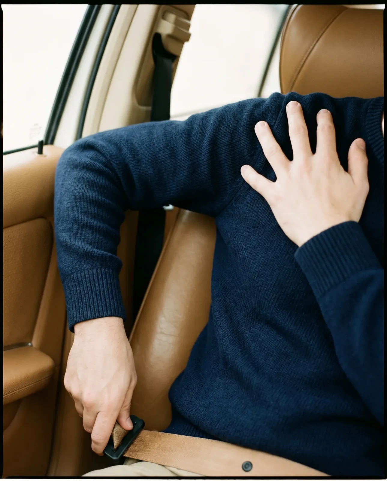 Person reaching across their body for a seatbelt while holding the top of their shoulder